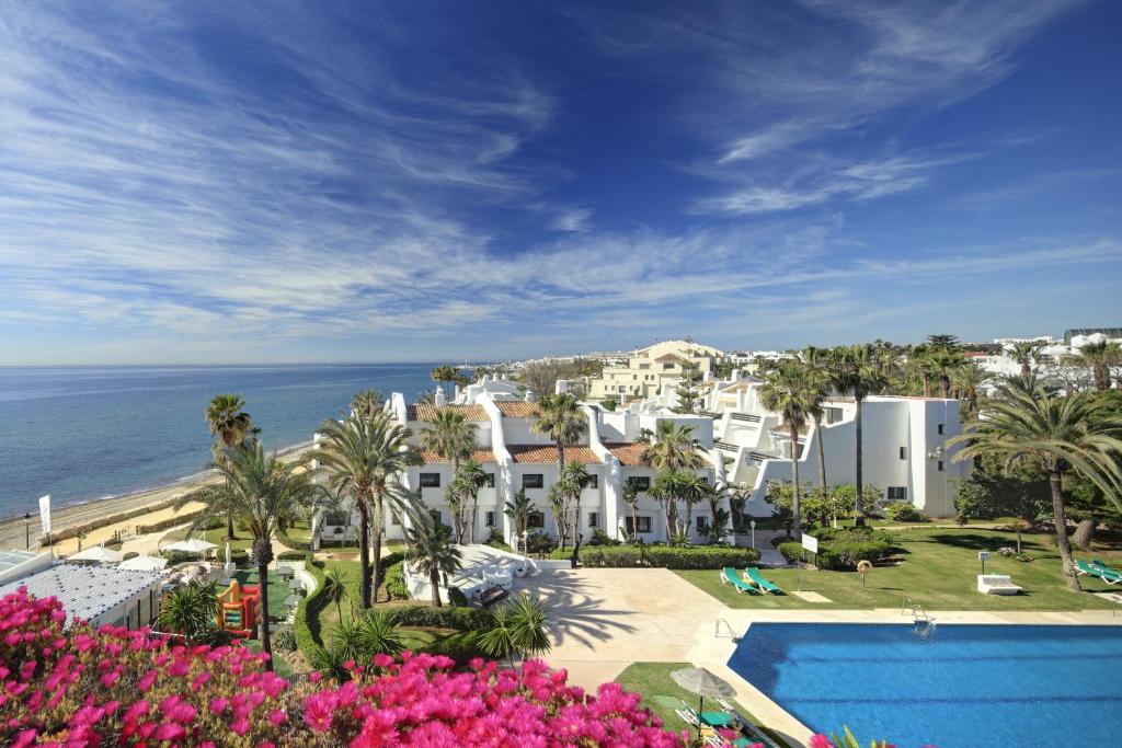 a view of a resort with a swimming pool and the ocean at Coral Beach Aparthotel in Marbella