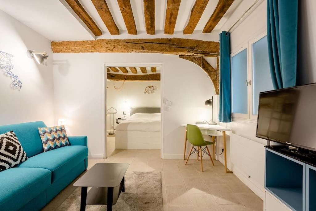 un salon avec un canapé bleu et une chambre dans l'établissement Appartement cosy proche Beaubourg, à Paris