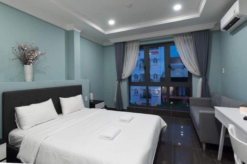 una camera da letto con un grande letto bianco e una finestra di NEW MILANO HOTEL & APARTMENT ad Ho Chi Minh