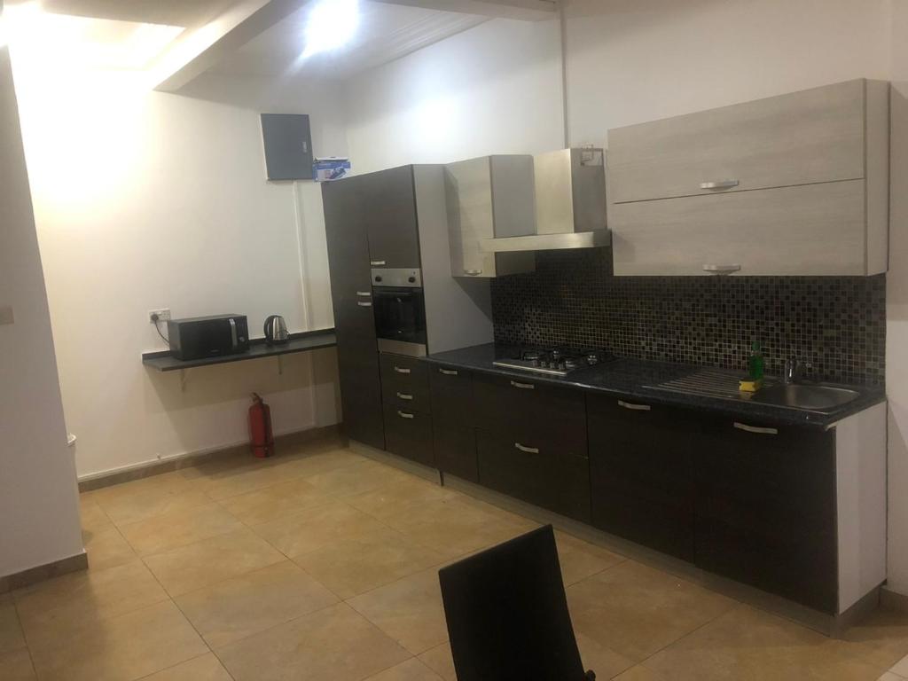 a kitchen with black and white cabinets and a stove at WILLS COURT in Accra