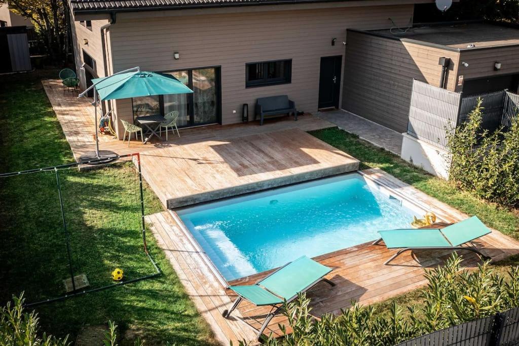 a swimming pool with two chairs and an umbrella at Maison meublée Divonne-les-Bains in Divonne-les-Bains