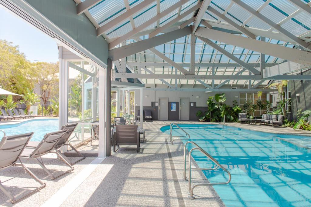 a swimming pool with chairs and a glass ceiling at Broadwater Resort WA Tourism Awards 2022 Gold Winner in Busselton