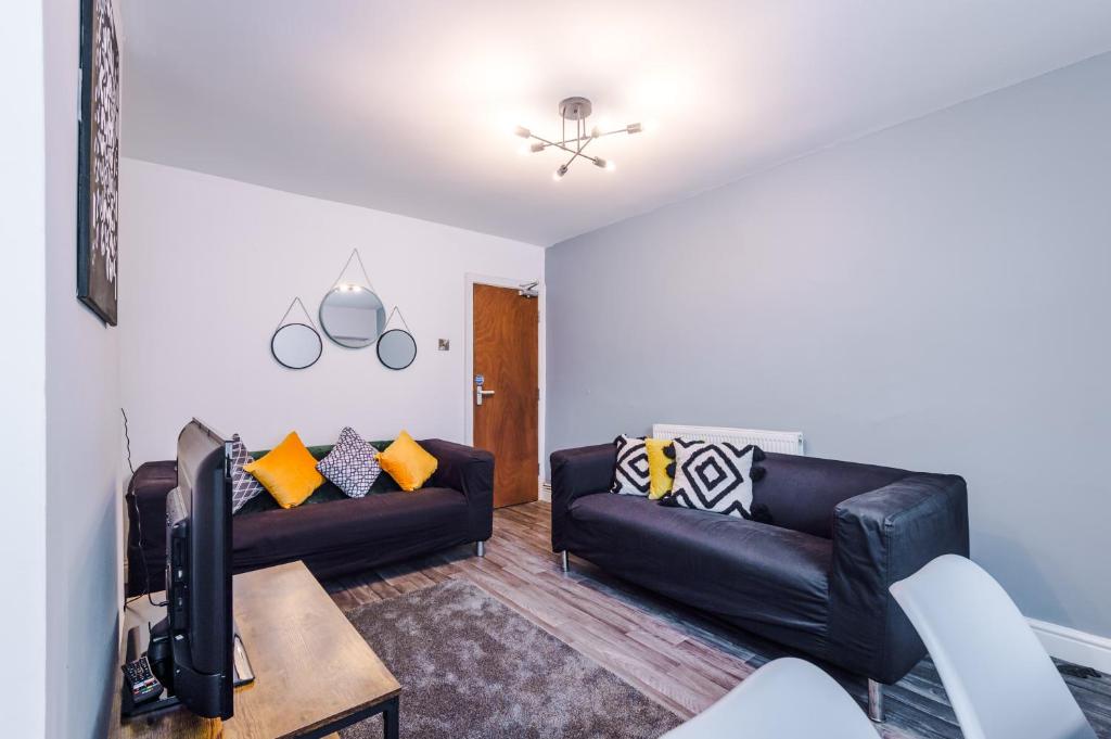 - un salon avec deux canapés en cuir noir et une télévision dans l'établissement Creative Cottage 4 BR PrimeStay, à Bolton