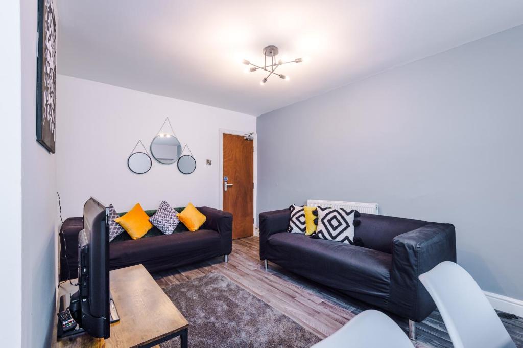 a living room with two black leather couches and a tv at Creative Cottage 4 BR PrimeStay in Bolton