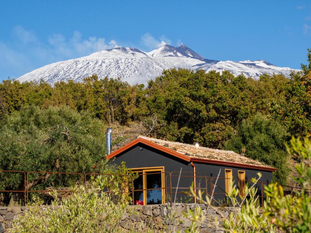 mały domek przed pokrytą śniegiem górą w obiekcie PODERE DELL'ETNA SEGRETA - Essential Nature Hotel w mieście Biancavilla