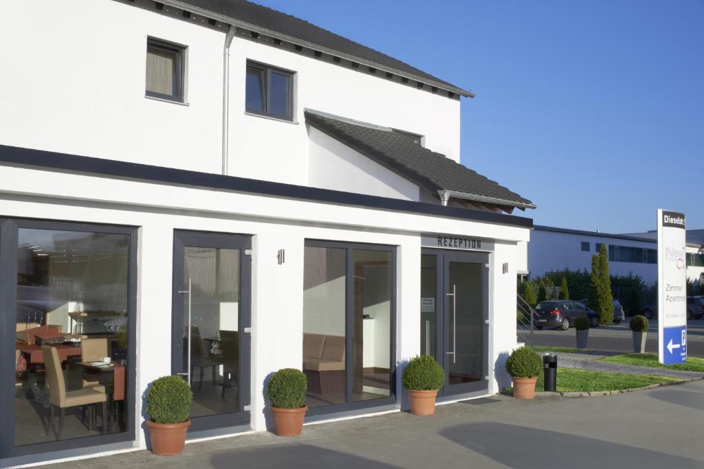 a white building with large windows and potted plants at Hotel New In Guesthouse in Ingolstadt