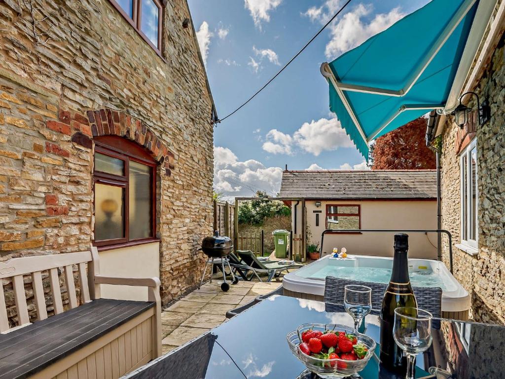 eine Terrasse mit einem Tisch mit einer Schale Obst und einer Flasche Wein in der Unterkunft 1 Bed in Ross-on-Wye 49910 in Walford