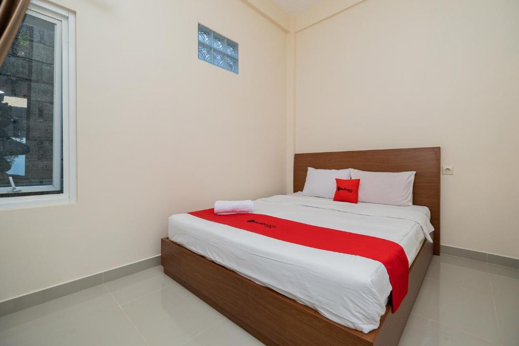 een slaapkamer met een bed met een rode deken bij RedDoorz Syariah near Batu Night Spectacular in Malang