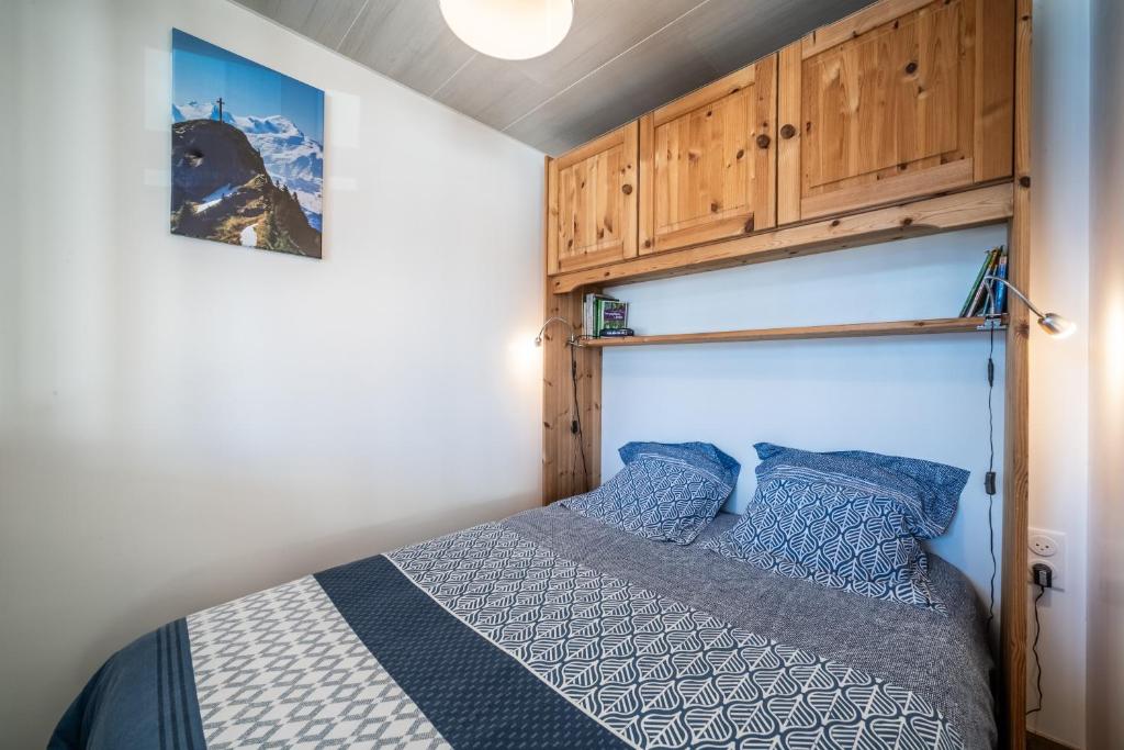 a bedroom with a bed and wooden cabinets at Les Mouflons 1500 in Taninges