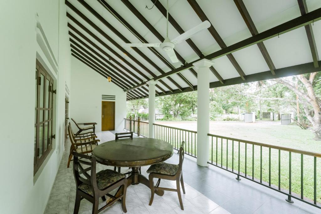 a dining room with a table and chairs on a balcony at Dias Legacy Bungalow in Talpe