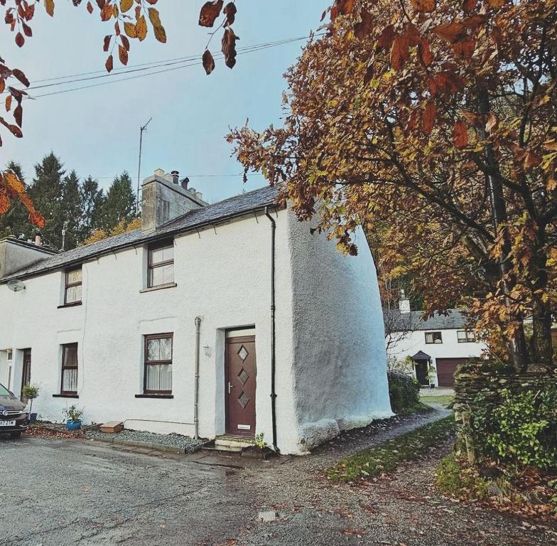 una casa bianca con una porta marrone su una strada di Bobtail Cottage by Woodland Park a Staveley