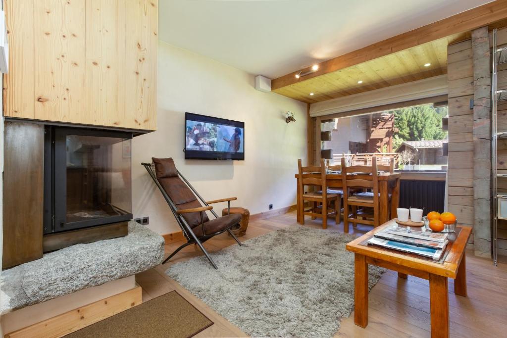 a living room with a fireplace and a table at Résidence Améthystes A2 ski in ski out - Happy Rentals in Chamonix-Mont-Blanc