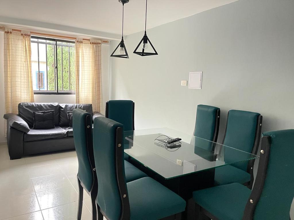 une salle à manger avec une table en verre et des chaises vertes dans l'établissement Hermoso y amplio apartamento en Niquia, à Bello