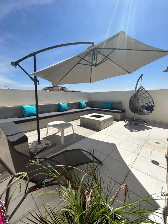a patio with a table and an umbrella at Appartement Gold moderne avec hammam centre ville in Agadir