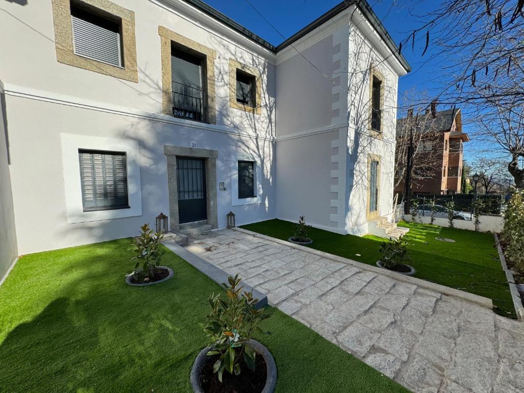 duży biały dom z zielonym dziedzińcem w obiekcie La Casita de Sofia w mieście El Escorial