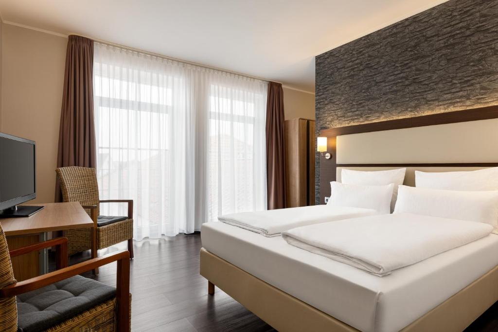 a hotel room with a large bed and a television at Amedia Express Bielefeld, Trademark Collection by Wyndham in Werther