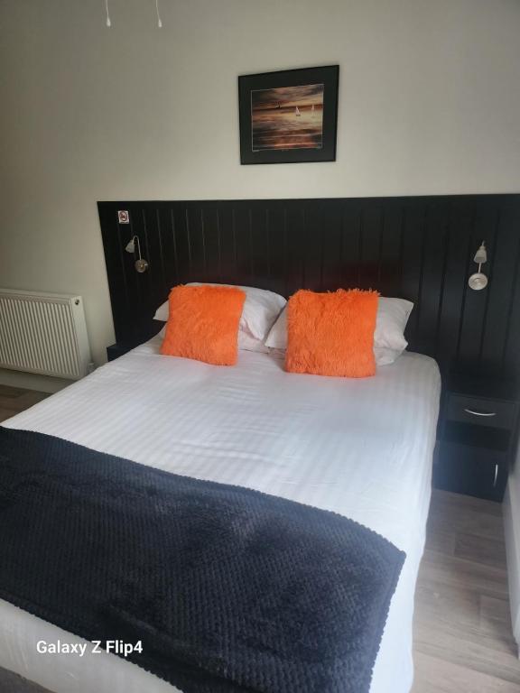 Una cama con dos almohadas naranjas encima. en The Dock Hotel en Amble