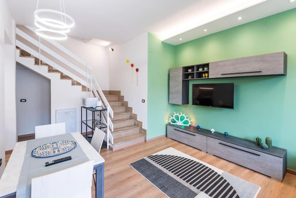 sala de estar con pared verde y TV en I Pumi Apartment & Free Parking - Lecce Selection, en Lecce