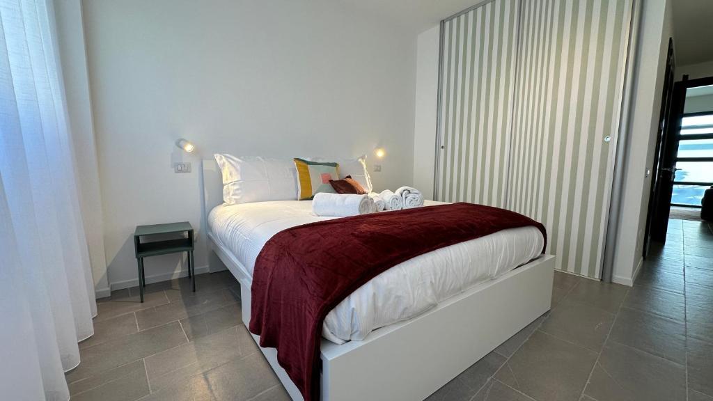 1 dormitorio con cama blanca y manta roja en CaseOspitali - Casa Navigli Watt, vicino al Naviglio, originale e luminoso bilocale per 4 con tutti i comfort, en Milán