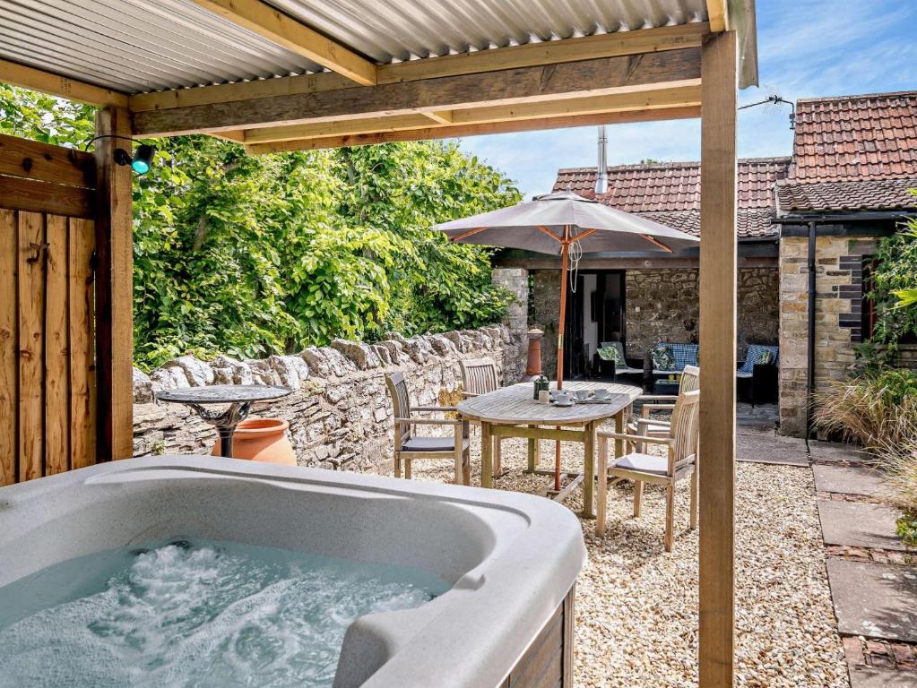 a bath tub on a patio with a table and an umbrella at 2 Bed in Wedmore 51342 in Chapel Allerton