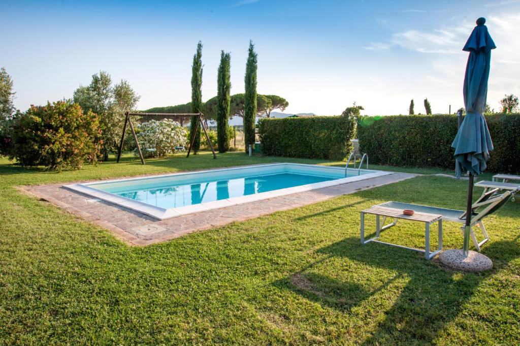 a pool in a yard with an umbrella and a swing at Le Gerlette - Il Granaio in Braccagni