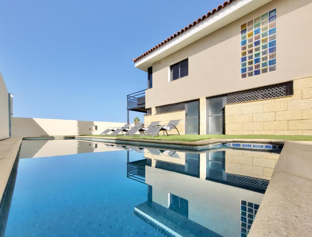 a building with a swimming pool with chairs next to it at Miya del Sol Heated Saltwater Pool in La Orotava