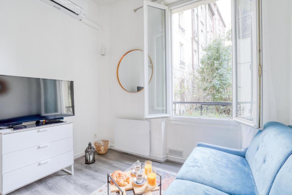 a living room with a blue couch and a tv at Chic Appartement Climatisé à 10 Minutes de Paris: Confort et Élégance in Maisons-Alfort