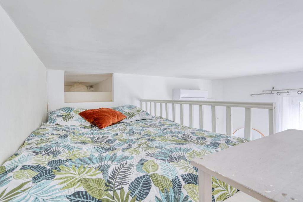 an orange pillow on a bed in a bedroom at Chic Appartement Climatisé à 10 Minutes de Paris: Confort et Élégance in Maisons-Alfort