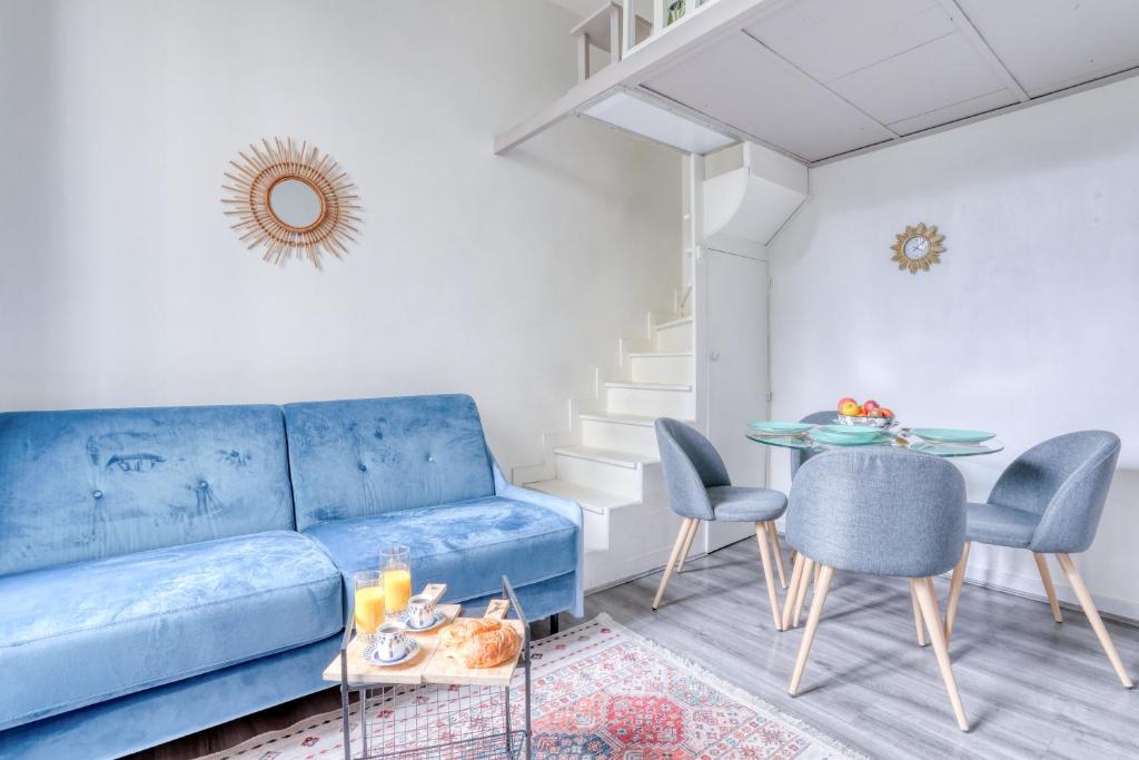 - un salon avec un canapé bleu et une table dans l'établissement Chic Appartement Climatisé à 10 Minutes de Paris: Confort et Élégance, à Maisons-Alfort