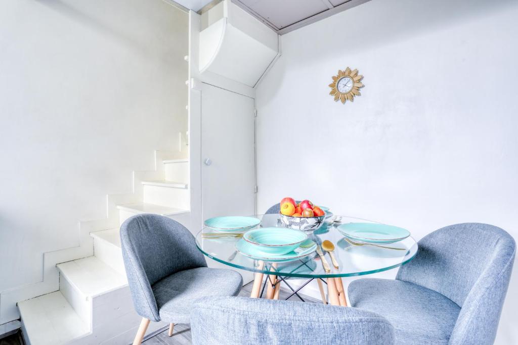 a dining room with a glass table and two chairs at Chic Appartement Climatisé à 10 Minutes de Paris: Confort et Élégance in Maisons-Alfort