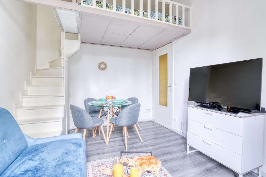 a living room with a table with chairs and a tv at Chic Appartement Climatisé à 10 Minutes de Paris: Confort et Élégance in Maisons-Alfort
