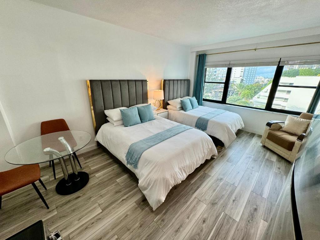 2 Betten in einem Zimmer mit einem Tisch und einem Stuhl in der Unterkunft Directly on the Beach with Pool & Parking in Miami Beach