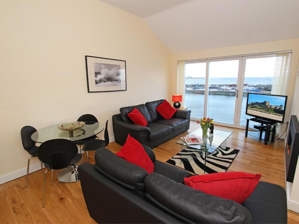 a living room with a black couch and red pillows at 2 Bed in Seahouses CN198 in Seahouses