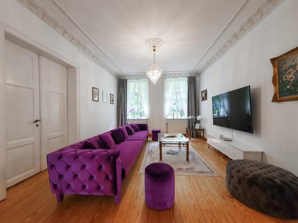 a living room with a purple couch and a tv at DEUTSCHE VILLA - DELUXE APARTMENT mit Sauna und großem Garten in Rostock