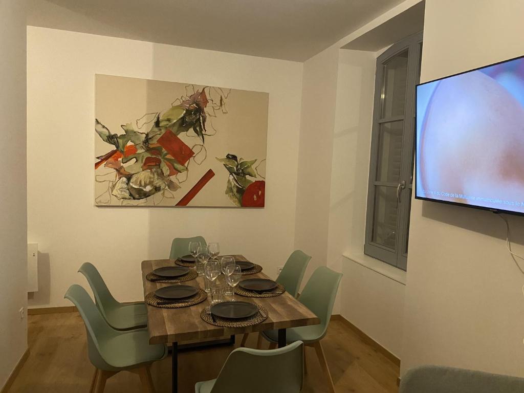 Royat : Superbe appartement en face des Thermes في رويات: غرفة طعام مع طاولة وتلفزيون بشاشة مسطحة
