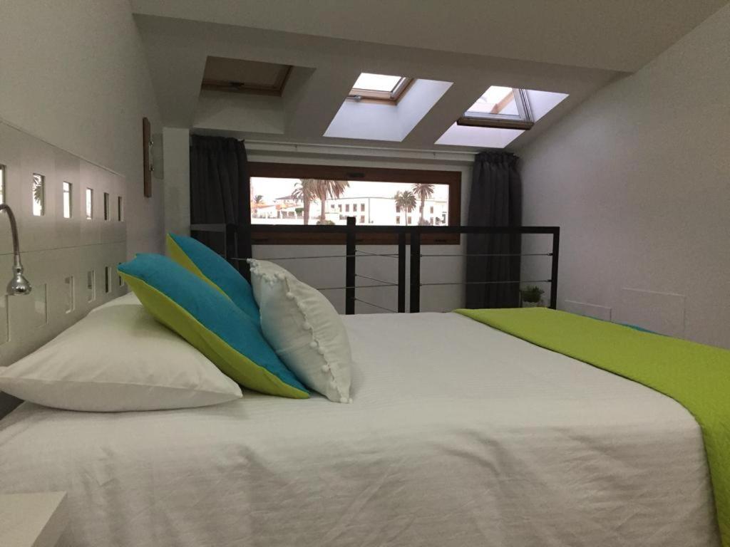 una camera da letto con un letto bianco con cuscini blu e verdi di loft bailadero a Telde