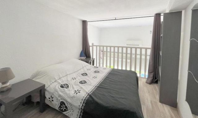 a bedroom with a bed and a desk and a balcony at Agréable maison avec terrasse et piscine collective -6PQ32 in Le Barcarès