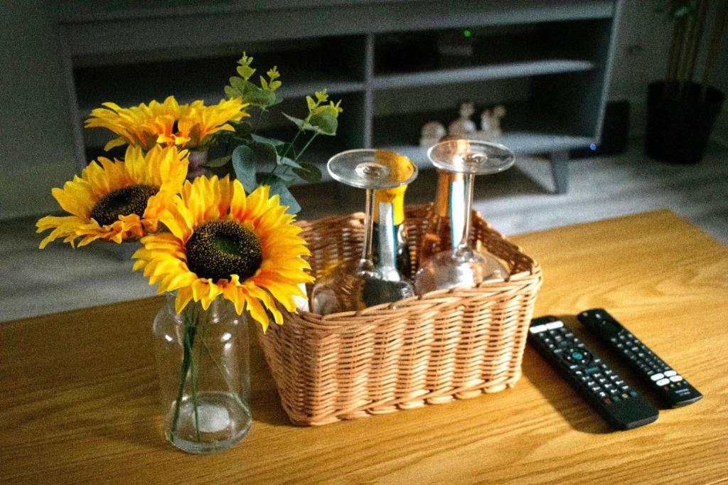 een mand met zonnebloemen en flessen op een tafel bij Watford Cozy Full Home W Parking - Perfect for Harry Potter Studios! in Leavesden Green