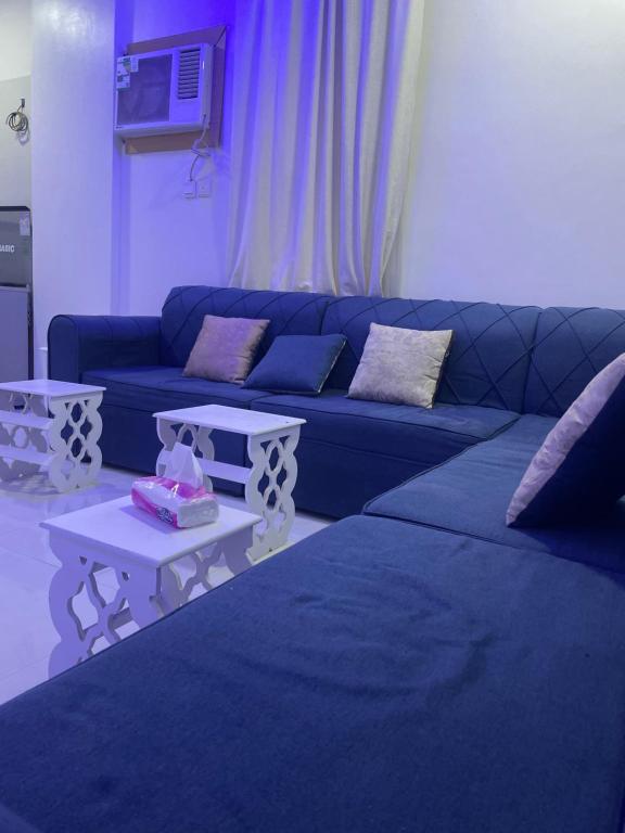 a living room with a blue couch and two tables at الجامعين ستار in Ruqaiqah