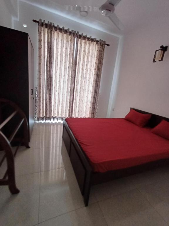 a bedroom with a red bed and a window at 3B in Dehiwala