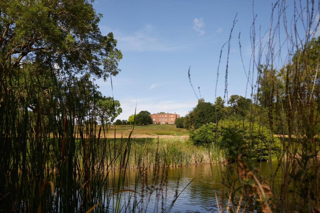 Blick auf einen Teich mit einem Haus im Hintergrund in der Unterkunft The Grove in Chandler's Cross