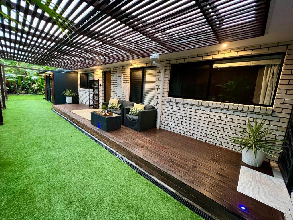un patio extérieur avec un auvent et une terrasse en bois dans l'établissement Private Gem in Pacific Pines, à Gold Coast
