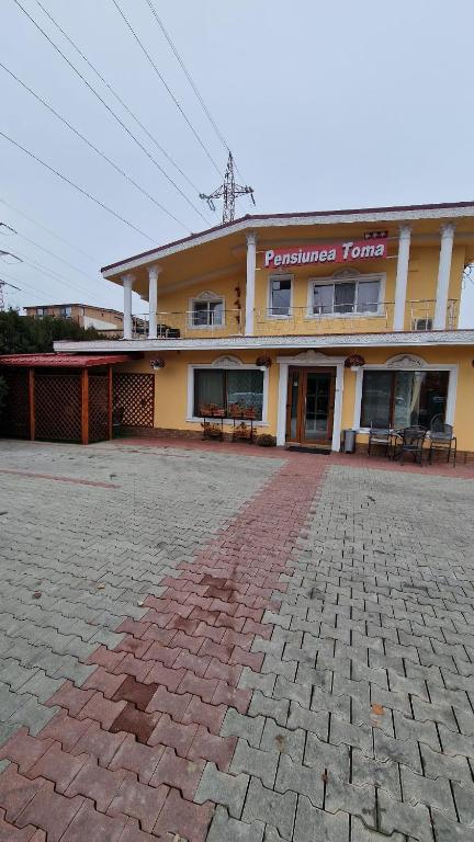 ein großes gelbes Gebäude mit einer Backsteineinfahrt davor in der Unterkunft Pensiunea Toma in Ploieşti