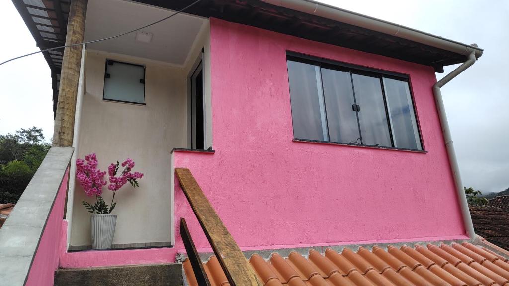 a pink house with a window and a vase of flowers at Chalé rosa in Resende