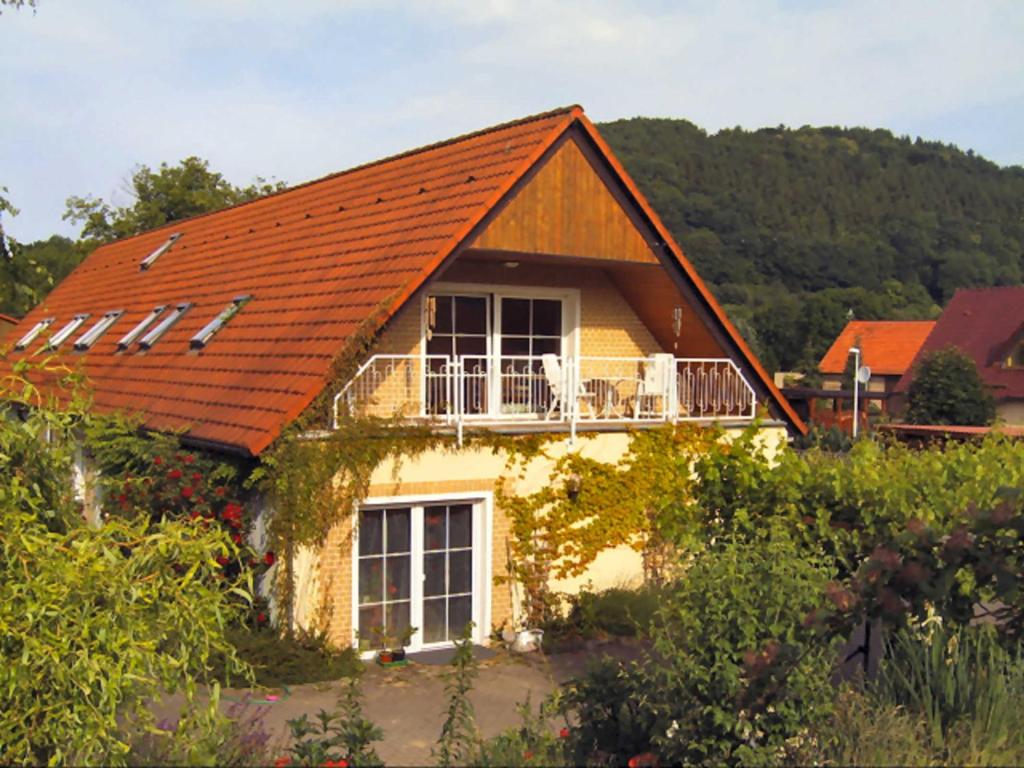 une maison avec un toit orange et un balcon dans l'établissement Ferienwohnung Hüttenhof Großleinungen, 