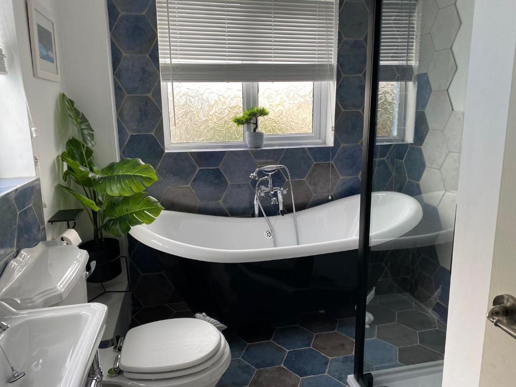 a bathroom with a tub and a toilet and a window at Lobster Cottage - Stylish 3 Bedroom Cottage in heart of Tenby Town, Pembrokeshire in Pembrokeshire