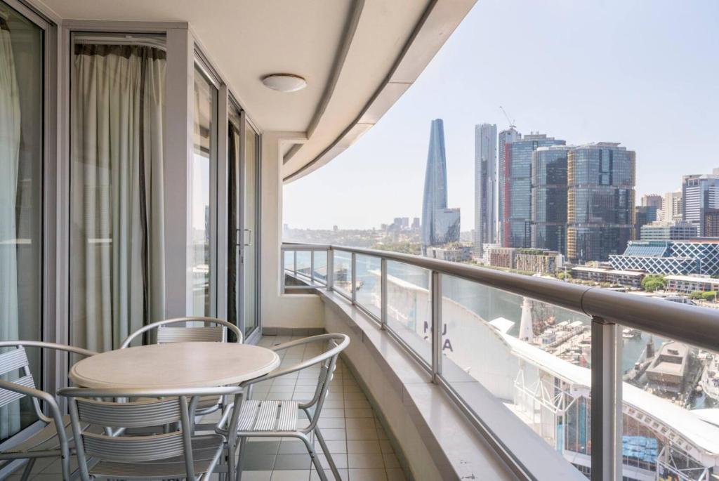 een balkon met tafels en stoelen en uitzicht op de stad bij Spectacular Darling Harbour View Apartment & Parking in Sydney