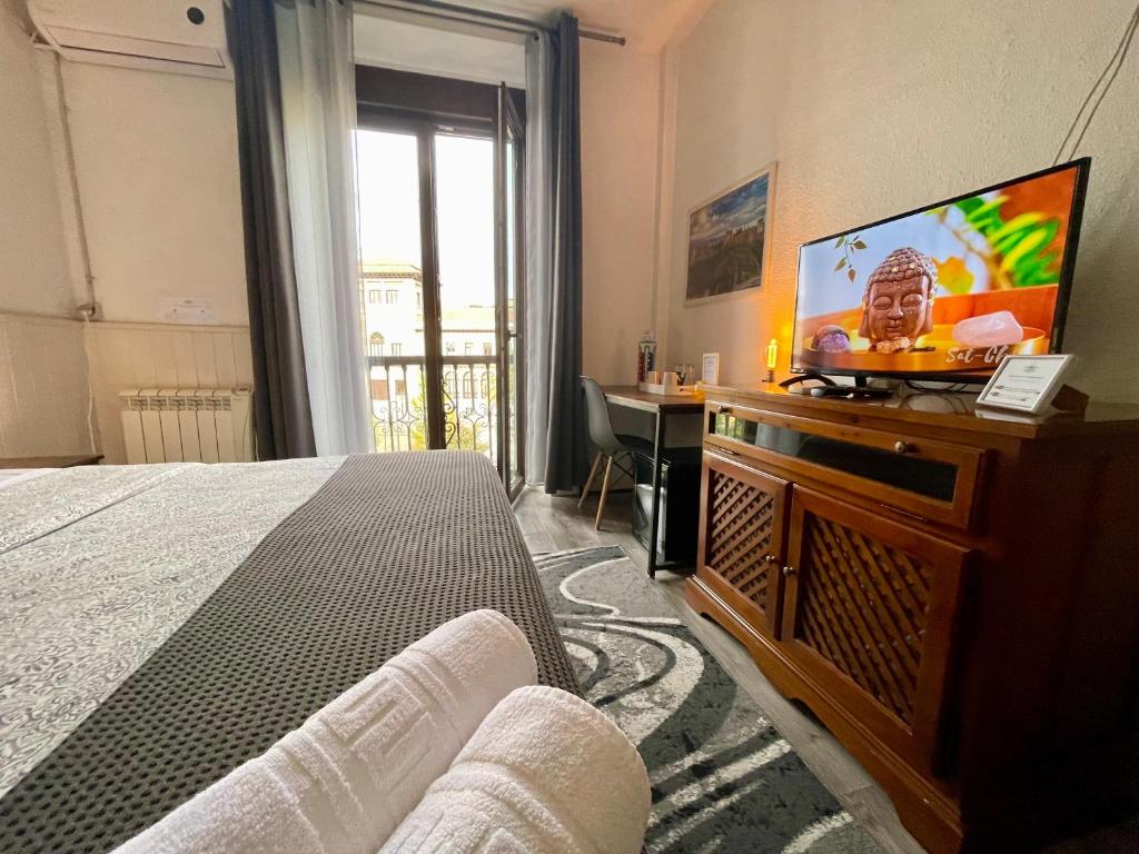 1 dormitorio con 1 cama y TV de pantalla plana en Itinere Rooms, en Granada