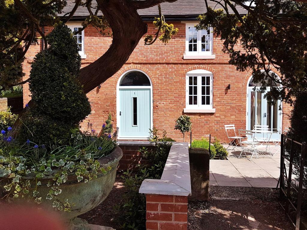 a brick house with a white door and a porch at Finest Retreats - No 1 Meynell Mews in Breedon on the Hill