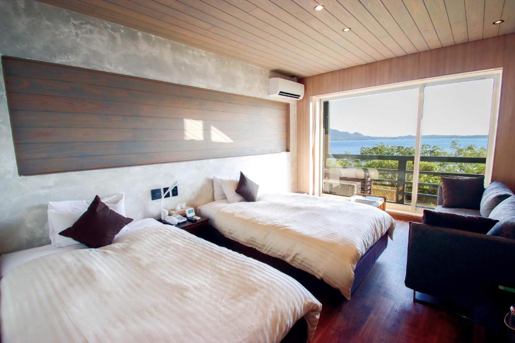 1 dormitorio con 2 camas, sofá y ventana en Petit Resort Native Sea Amami en Tatsugo